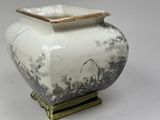 a white and black vase with a gold lid on a stand