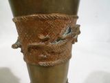 un vase en bronze orné d'un oiseau, posé sur une table