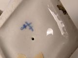 a hand holding a small white bowl with a smiley face on it