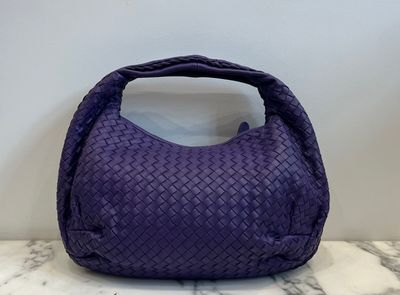 purple woven leather handbag on marble counter top
