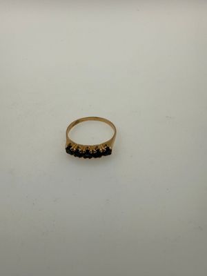 a gold ring with black stones sits on a white surface