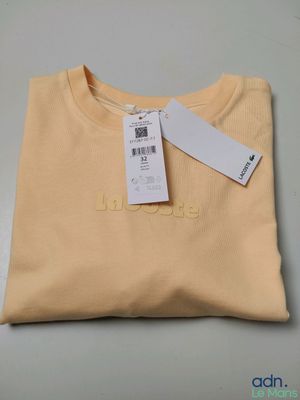 un t-shirt jaune avec une étiquette, posé sur une table