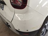the rear end of a white car with a damaged bumper
