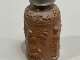 a small brown jar with a silver lid on a white surface