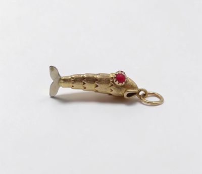a close up of a gold fish charm on a white surface