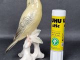 a yellow bird sitting on a branch next to a tube of lip bale