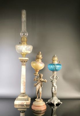 three antique lamps are sitting on a black surface with a gray background