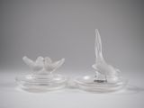two white birds sitting on clear plates on a table
