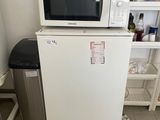 un petit réfrigérateur blanc surmonté d'un micro-ondes