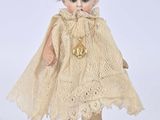 an antique doll with blonde hair wearing a cape and boots
