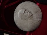silver medal with a portrait of a man in a suit in a box
