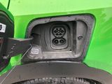 a close up of a green car with an electric charger plugged into it