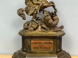 statue en bronze représentant un cheval et son cavalier, posée sur un socle en bois