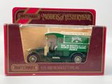 un petit camion vert dans une boîte rouge posée sur une surface blanche
