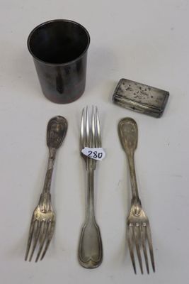 des couverts en argent posés sur une table, accompagnés d'une tasse et d'une cuillère