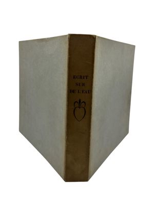 an old book with a gold cover sitting on top of a white table
