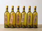 six bottles of wine with labels on them sitting on a wooden table
