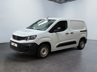 La camionnette blanche est garée dans une grande pièce au sol noir.