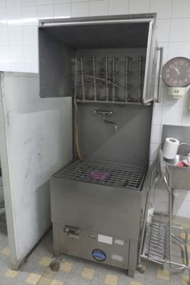 a large stainless steel machine in a kitchen with a clock on the wall