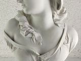 a white bust of a woman on a blue pedestal