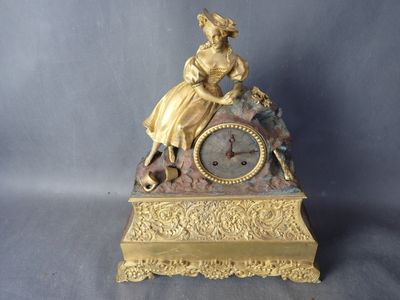 une horloge en or avec une femme assise dessus