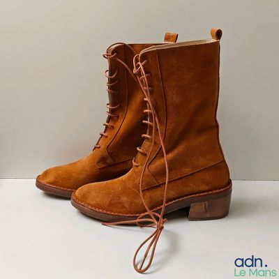 des bottes marron à lacets, posées sur une surface blanche