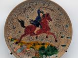 a plate with a painting of a woman riding a horse