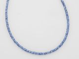 un gros plan d'un collier de perles bleues posé sur une surface blanche