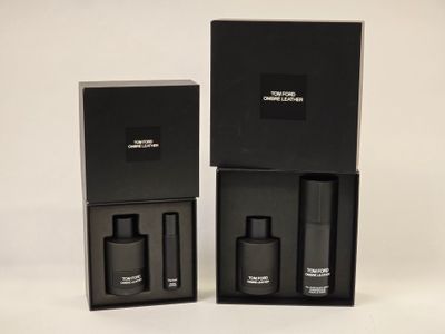 two black boxes with perfume bottles in them on a white surface