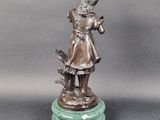 bronze statue of a girl with a bird on a marble base