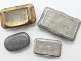 trois objets métalliques argentés posés sur une surface blanche, avec une pierre
