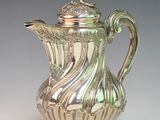 a silver coffee pot with a bird on top of it