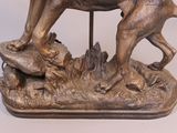 bronze statue of a dog on a rock with a bird in its mouth