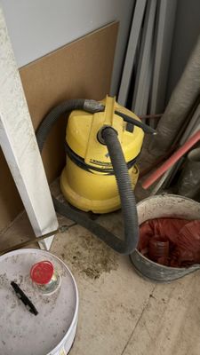 un seau de peinture et un aspirateur par terre