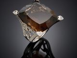 a large smoky quartz ring with diamonds on a black surface