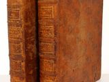 an old pair of books sitting on top of a white surface