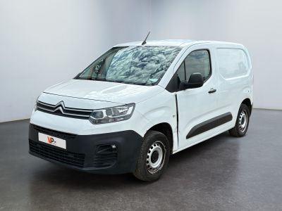La camionnette blanche est garée dans une grande pièce au sol noir.