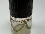 a small glass jar with a black lid on a white surface