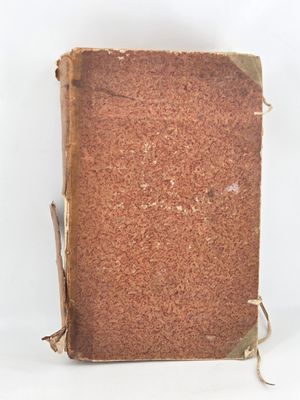 an old book sitting on top of a white table next to a white wall
