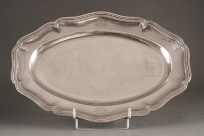 une assiette en argent posée sur un socle transparent, sur une table
