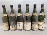 six bouteilles de vin sont alignées sur une table