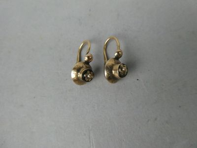 une paire de boucles d'oreilles en or sur une surface blanche