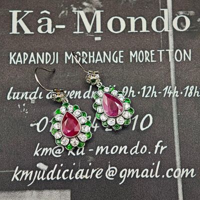 une paire de boucles d'oreilles roses et vertes exposée devant une enseigne « ka - mondo »