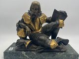 statue d'un homme en train de lire un livre, posée sur un socle en marbre