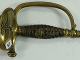 a gold sword with a black handle on a white surface