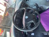 a car dashboard with a steering wheel and a purple pillow