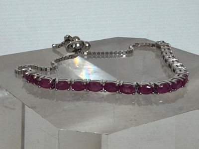 un bracelet en argent orné de pierres roses, posé sur une table