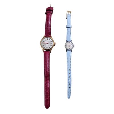 a couple of watches sitting next to each other on a white surface