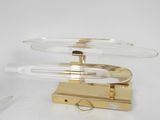 a clear glass lamp with a gold base on a white table
