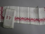 three white towels with red designs on them on a table